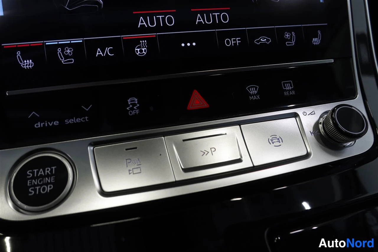 Yksityiskohta: Keskikonsolin näppäimet: START ENGINE STOP -painike, drive select -valitsin, sähköinen parkkijarru ja >>P-painike ilmastointipaneelin alla.