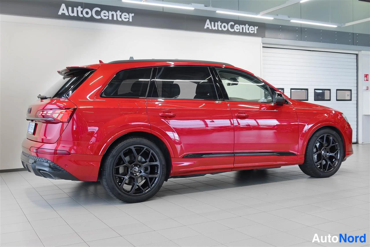 Takaviisto: Punaisen Audi Q7:n takakulmanäkymä sisätilassa, mustat kevytmetallivanteet ja takavalot näkyvät.