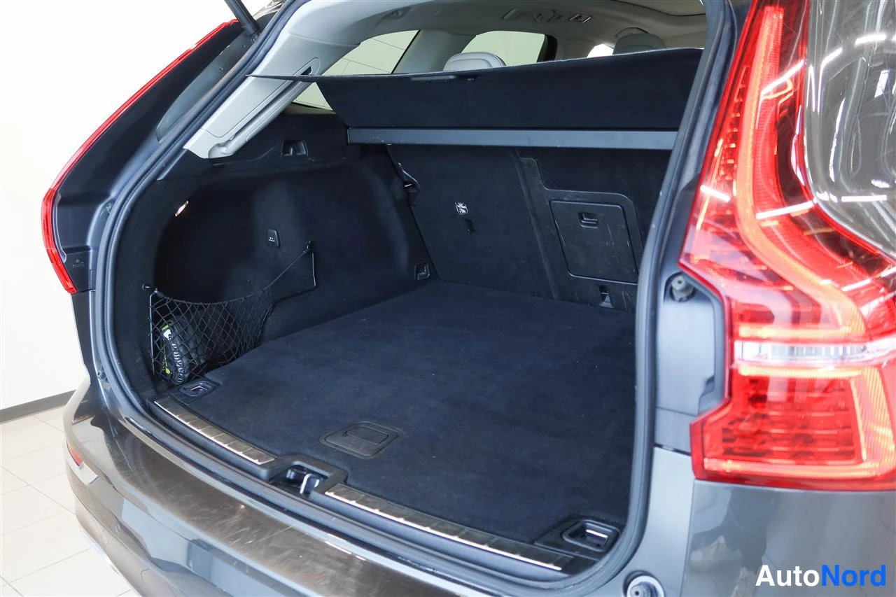Takaa: Volvo XC60:n avattu tavaratila, tumma matto ja sivuverkko näkyvissä.