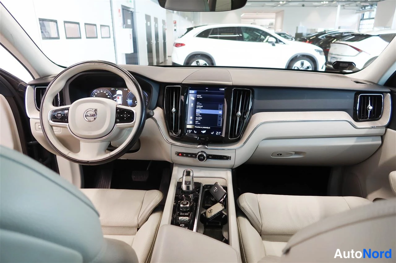 Muu: Auton sisätilat: beige kiltti-kojupaneeli, Volvo-ohjauspyörä, keskikonsolin infotainment-näyttö ja automaattivaihteen valitsin.