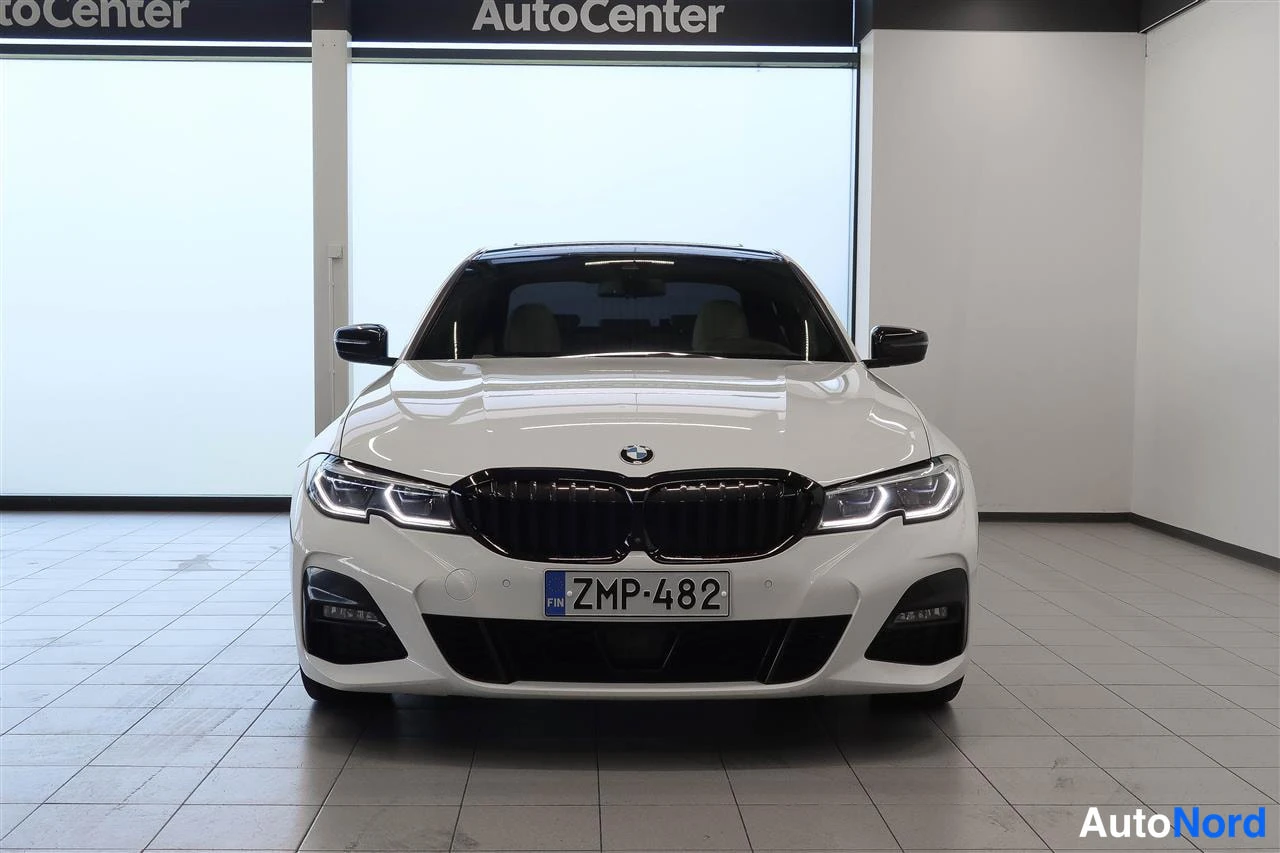 Edestä: Valkoinen BMW:n etunäkymä suoraan edestä, musta munuais­säleikkö, LED-etuvalot ja -kilpi.
