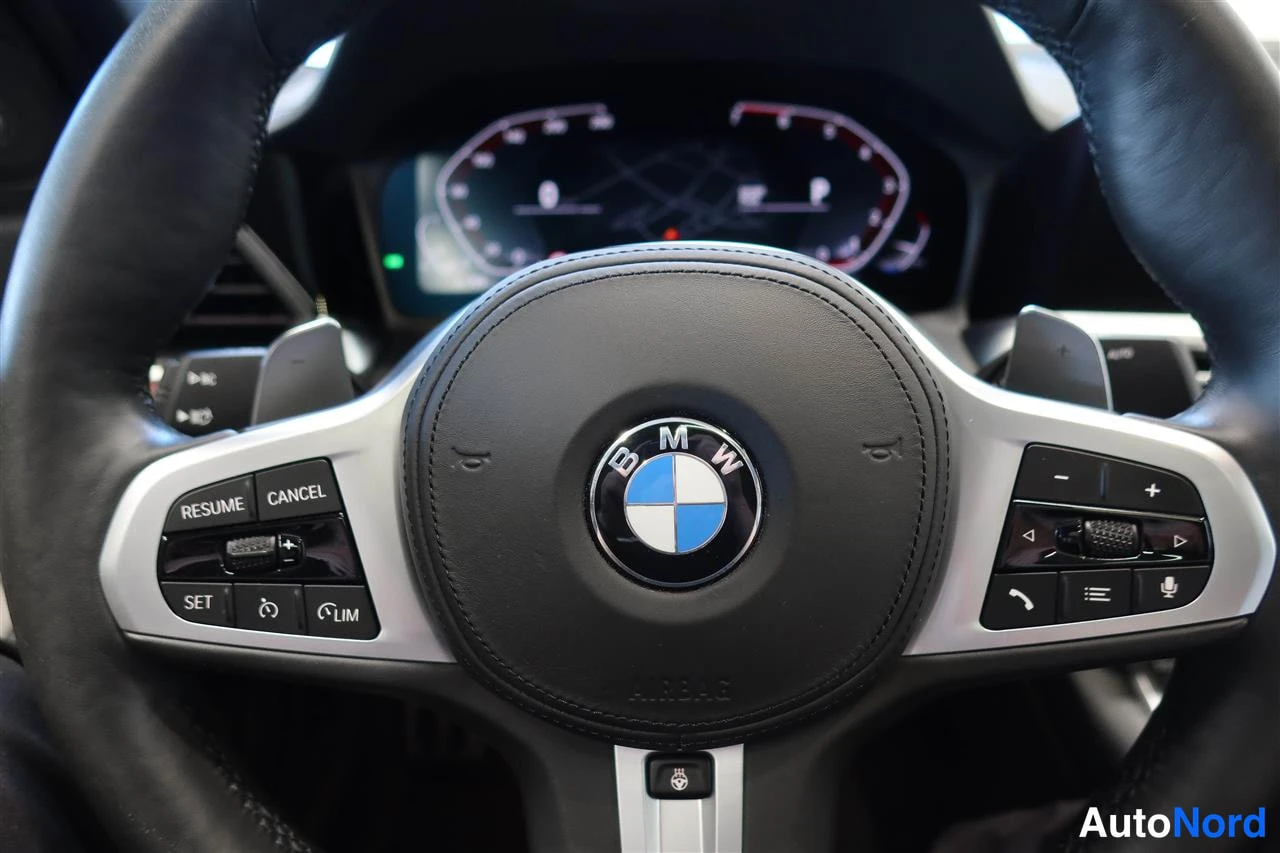 Muu: BMW-ohjauspyörän lähikuva, jossa MSI-tekstillä varustettu nappi ja monitoiminapit, mittaristo taustalla.