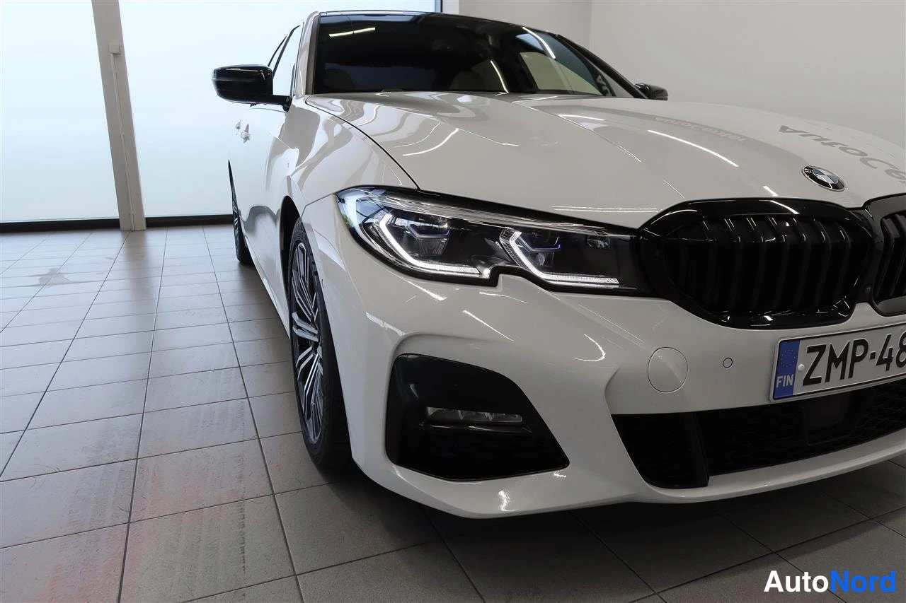 Etuviisto, nokka oikealle: Lähikuva valkoisen BMW:n etuosasta ja etupyörästä, LED-etuvalo ja musta säleikkö.