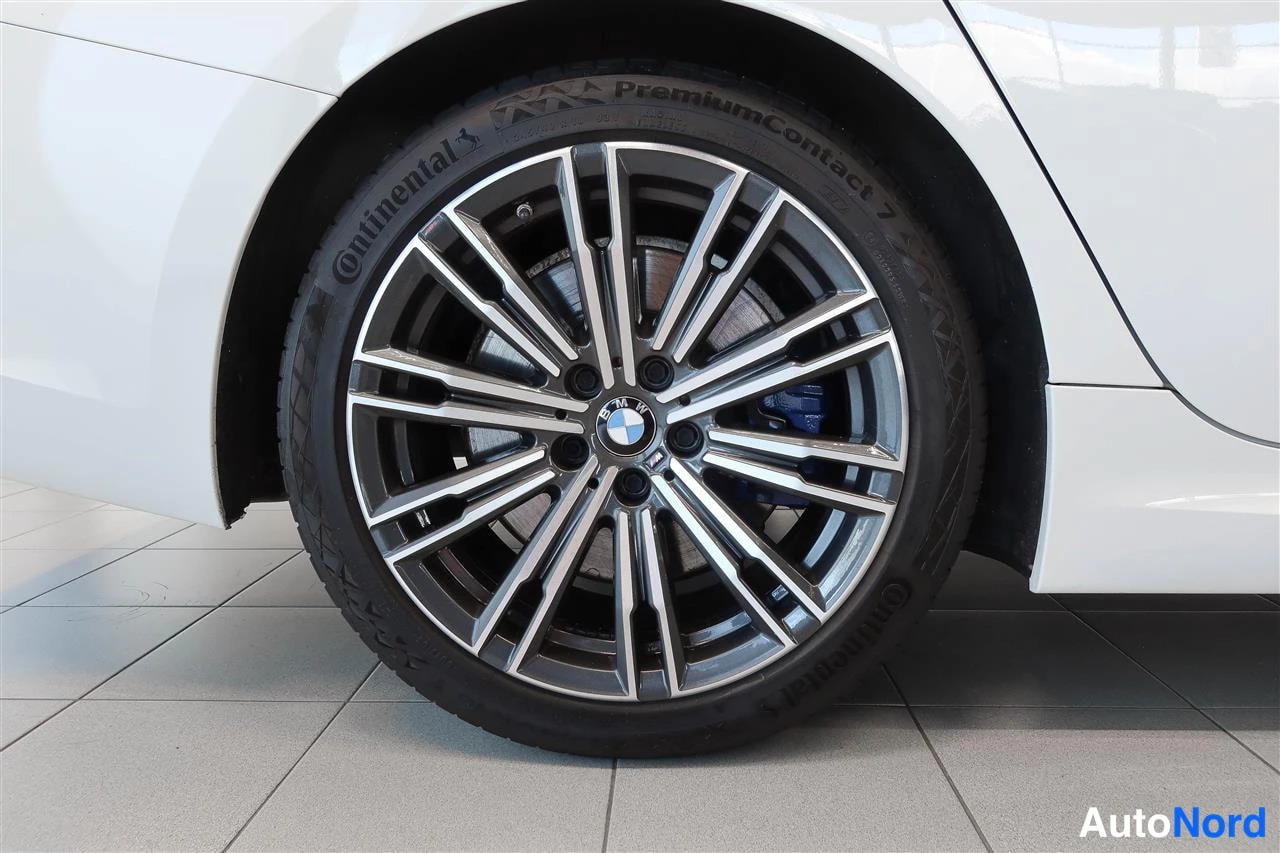 Yksityiskohta: BMW:n takapyörän lähikuva: kaksivärinen kimaraeanneke, Continental PremiumContact 7 -rengas ja sininen jarrusatula näkyvät.