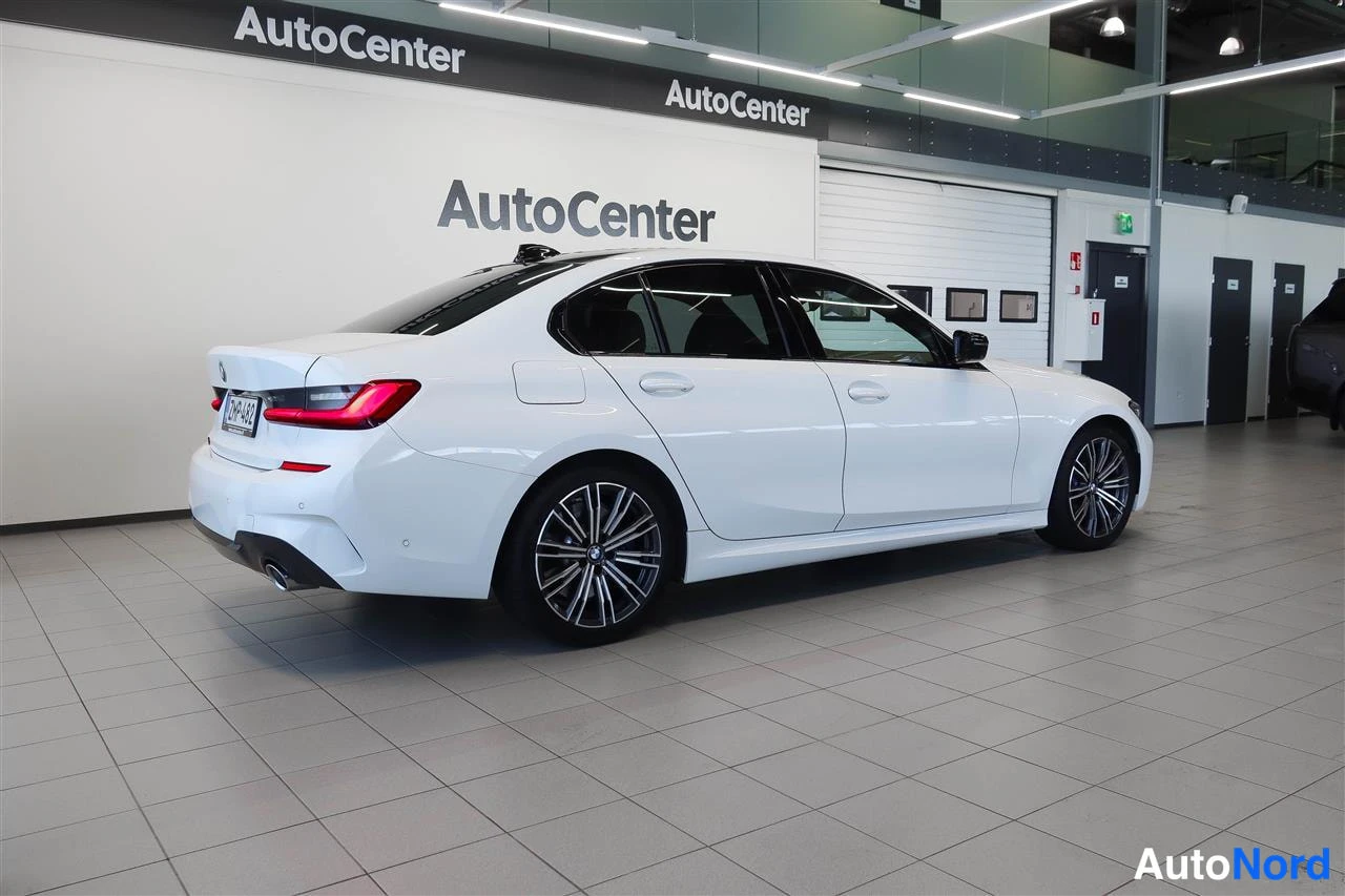 Takaviisto: Valkoinen BMW 330 -sedan takaosa ja kylki, rekisterikilpi, AutoCenter-hallissa.