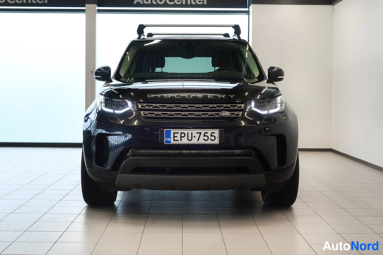 Edestä: Land Rover Discovery, musta, suora etukuva, katolla telineet, rekisteri.