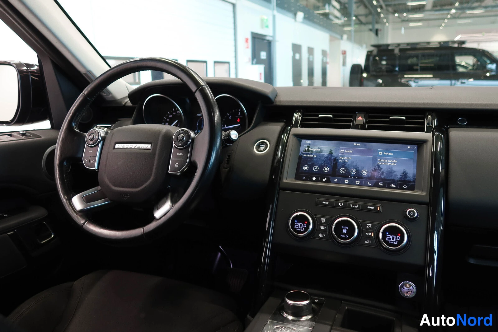 Muu: Ohjaamo vasemmalta kuvattuna: monitoimiratti, infonäyttö ja kaksivyöhykeilmastointi, näytössä A/C ja 20 astetta.
