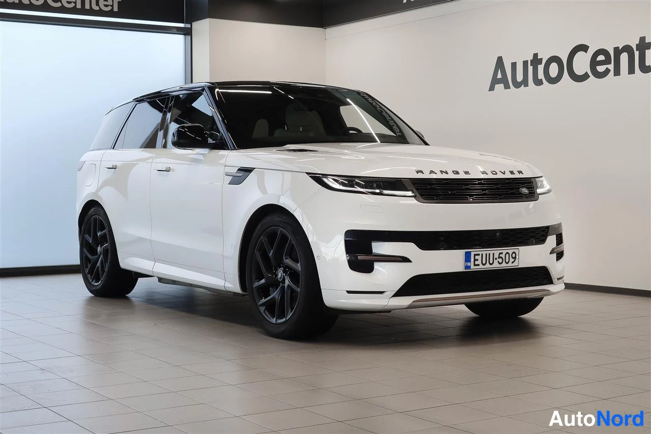 Etuviisto, nokka oikealle: Valkoinen Land Rover Range Rover Sport kuvattu edestä kolmannelta sivulla sisätiloissa; mustat vanteet ja kilpi.