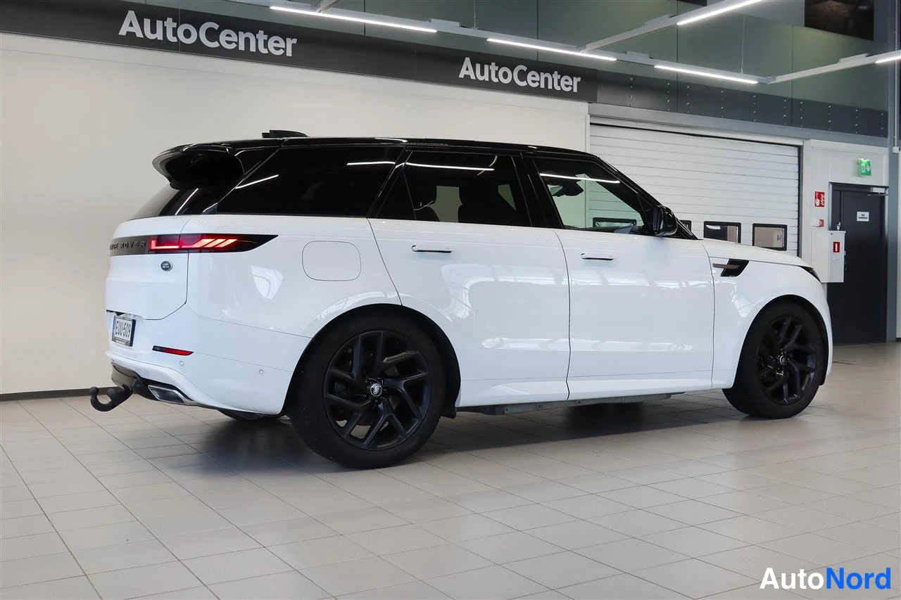 Takaviisto: Valkoinen Land Rover Range Rover Sport takaa vasemmalta nähtynä mustalla katolla ja mustilla vanteilla AutoCenter-hallissa.