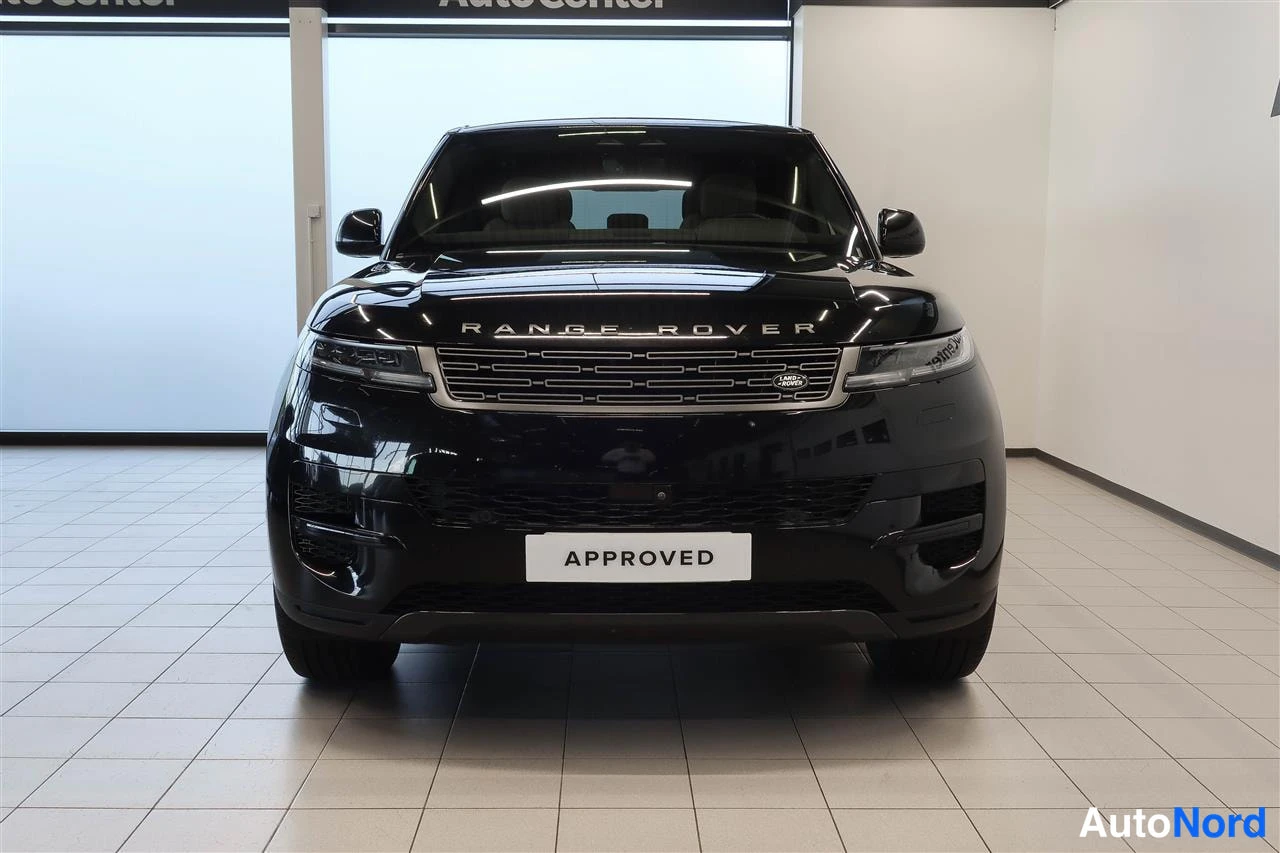 Edestä: Edestä kuvattu musta Land Rover Range Rover Sport, kayttöönottopyöräna APPROVED-kilpi.