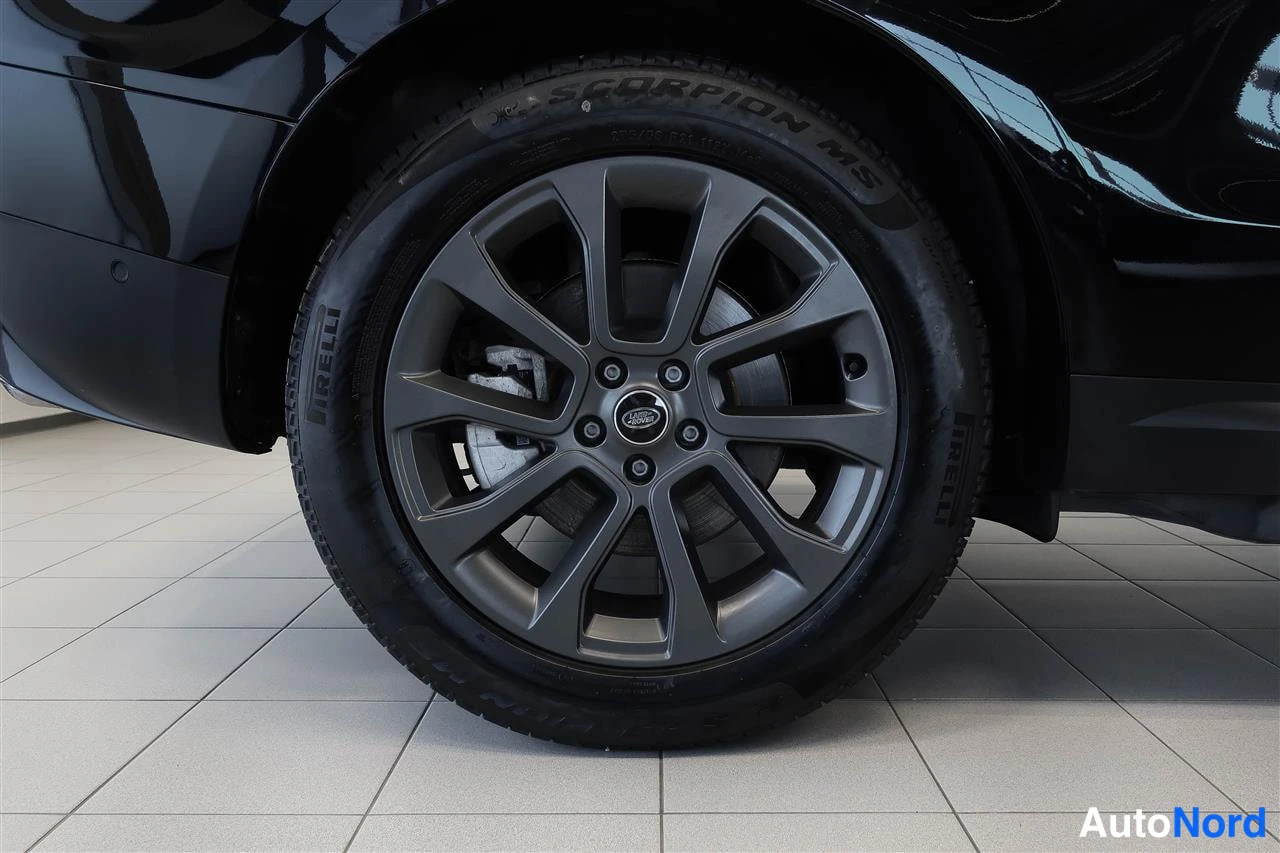 Yksityiskohta: Lähikuva auton tummasta vanteesta, jossa Land Rover -keskusaosa; Pirelli Scorpion MS -renkaan sivuseinä ja jarrusatula näkyvät.