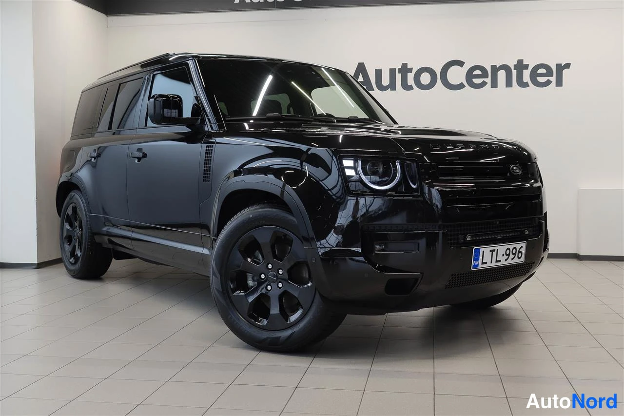 Etuviisto, nokka oikealle: Musta Land Rover Defender etukulmasta oikealta kuvattuna, valkoinen tausta ja AutoCenter-logo.