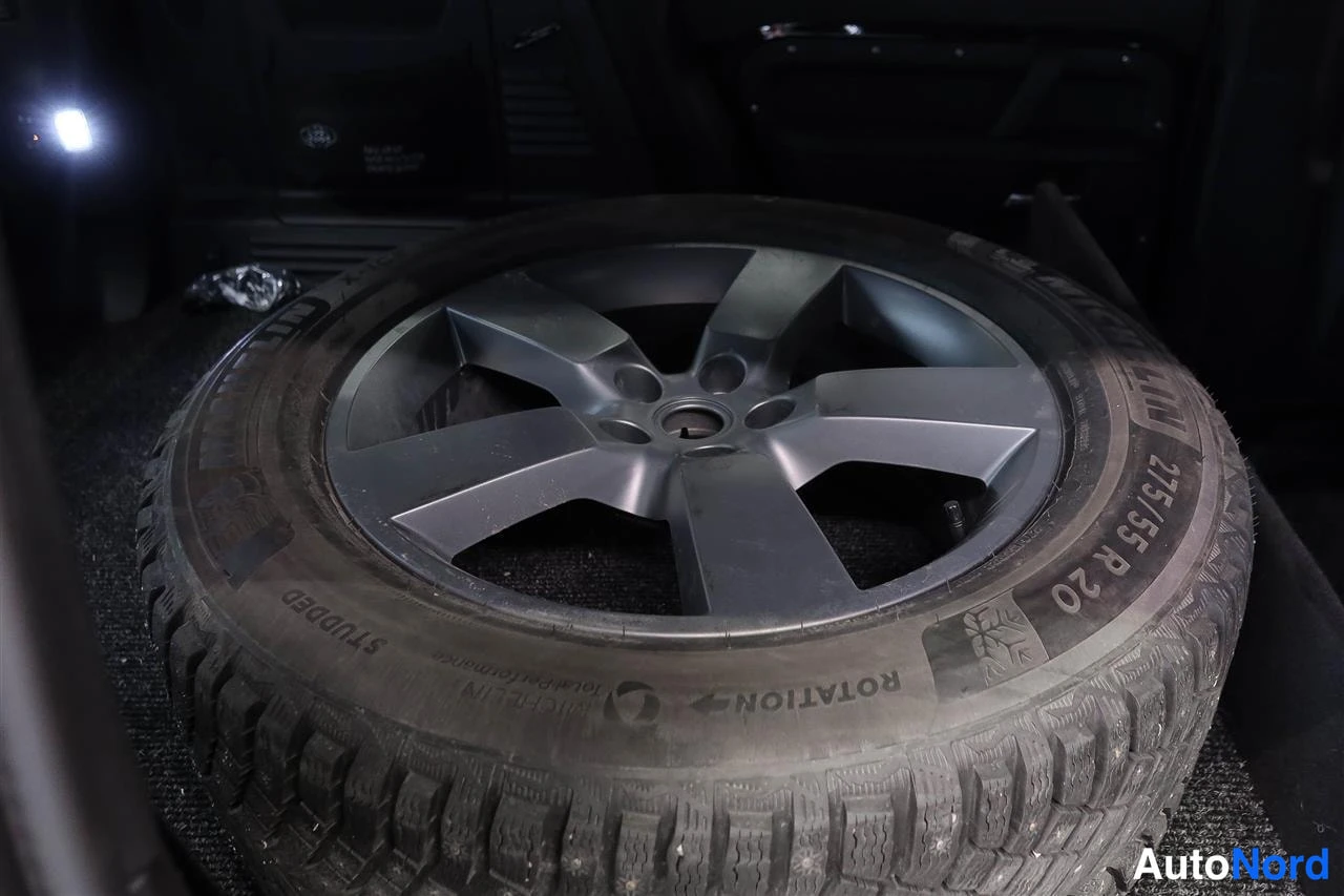 Yksityiskohta: Vararengas Michelin-nastarenkaalla (275/55 R 20), jossa tumma viisipuolainen vanteen alumiinivanne, kuvattu tavaratilassa.