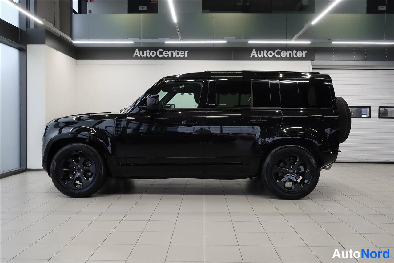 Sivulta: Mustan Land Rover Defenderin sivuprofiili autotallissa.