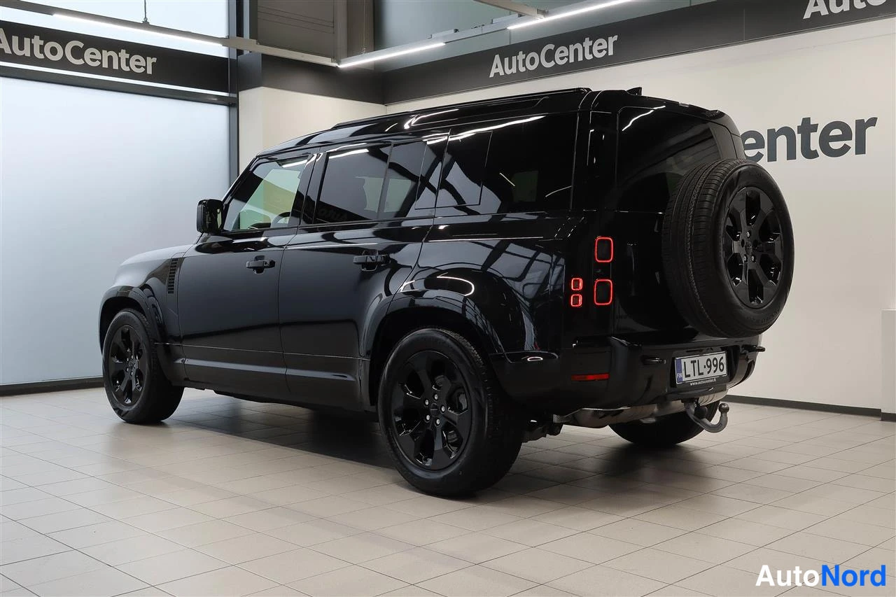 Takaviisto: Mustan Land Rover Defenderin takaosa ja vasen sivu autotallissa, rekisteritunnus.