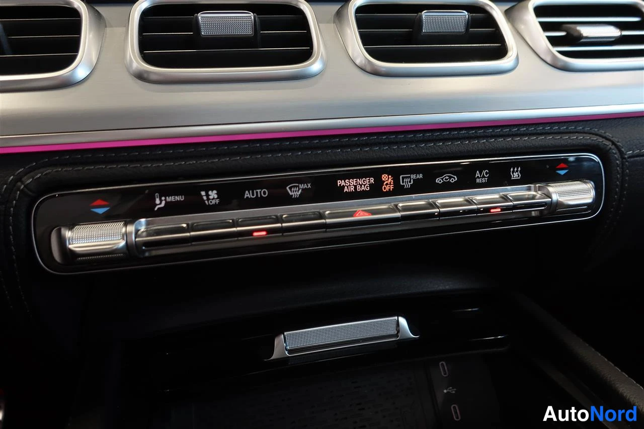 Yksityiskohta: Keskikonsolin ilmastointipaneeli AUTO- ja A/C-merkinnöillä, PASSANGER AIR BAG -varoitusvalolla ja tuska-punaisella äärivalolla.
