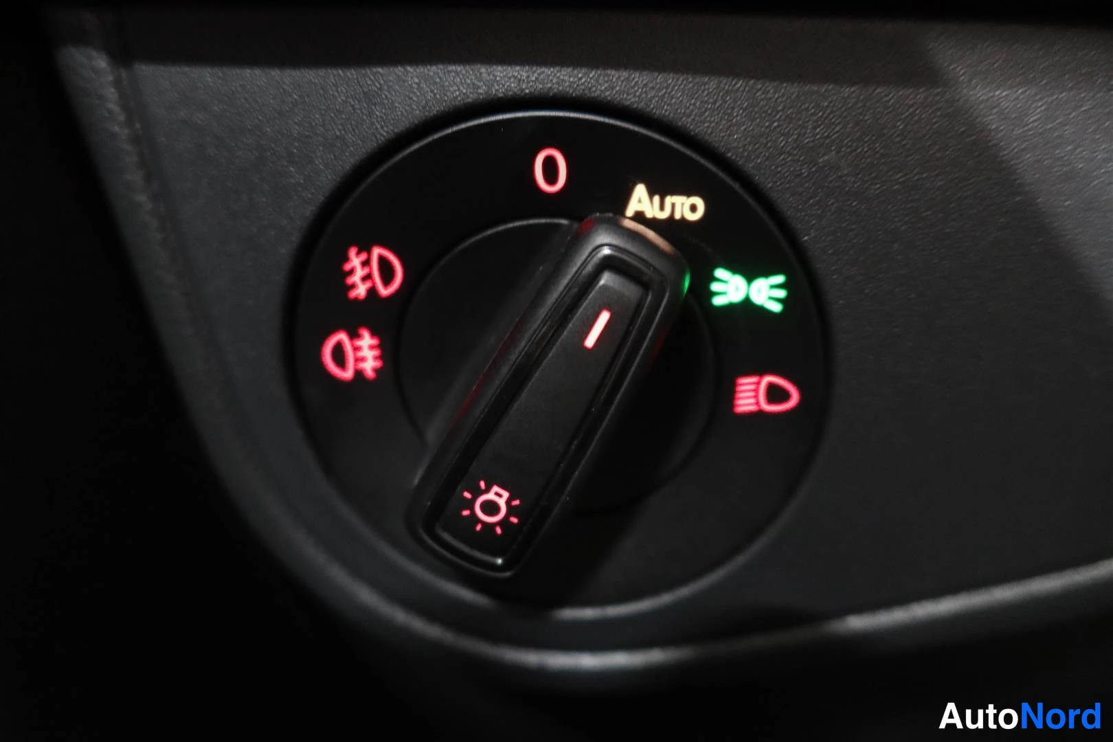 Yksityiskohta: Auton valaistuskytkin, jossa Auto-merkintä valaistuna vihreänä.