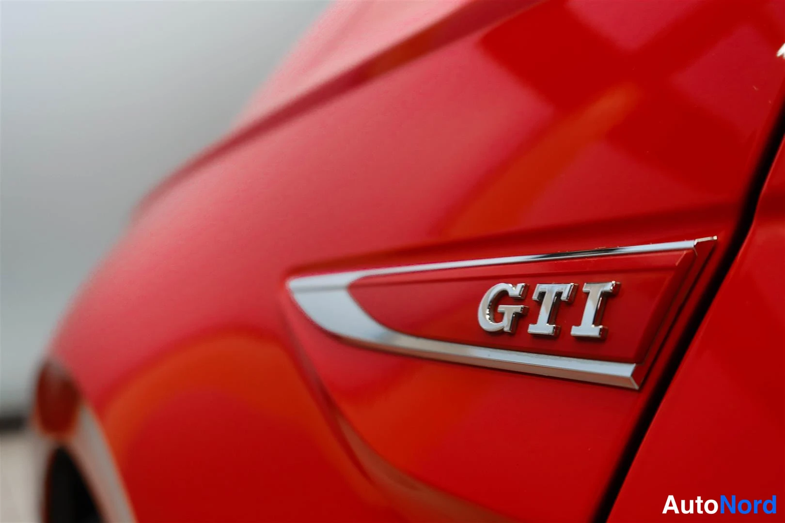 Moottoritila: Punaisen auton sivuilmoitin GTI-merkinnällä, lähikuva kiiltävästä pintakäsittelystä