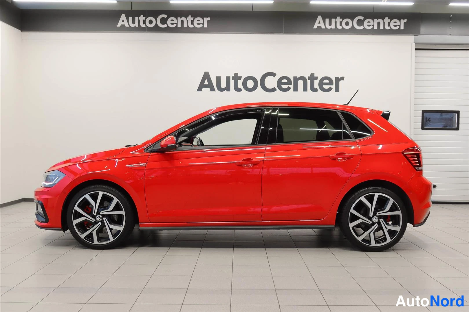 Sivulta: Punainen Volkswagen Polo sivulta oikealta kuvattuna näyttelytilassa.