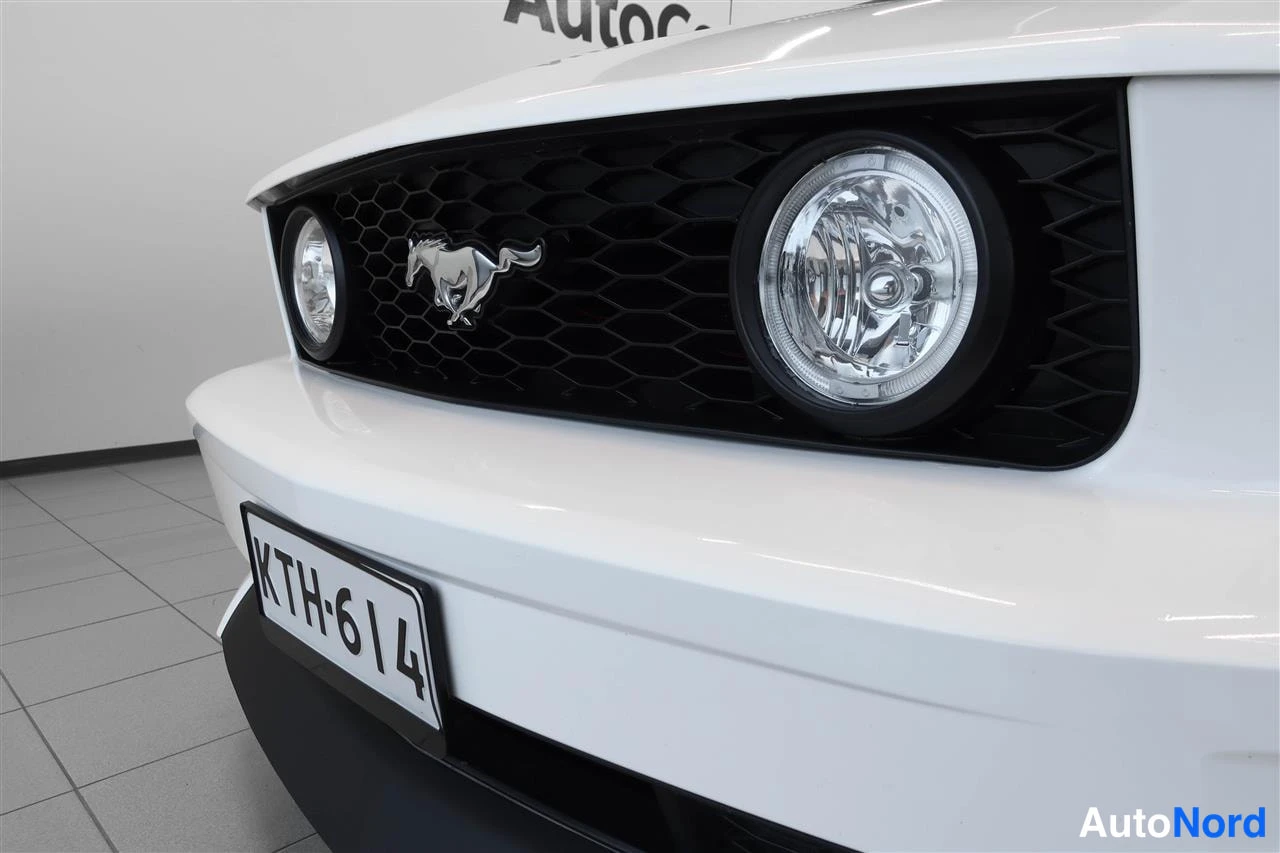 Edestä: Ford Mustangin etupuoli lähikuvassa: musta hunajakenkäänen etusäleikkö, vasemmalla näkyy osa toisesta pyöreästä etulyhdystä ja oikealla kuvassa oleva pyöreä etu