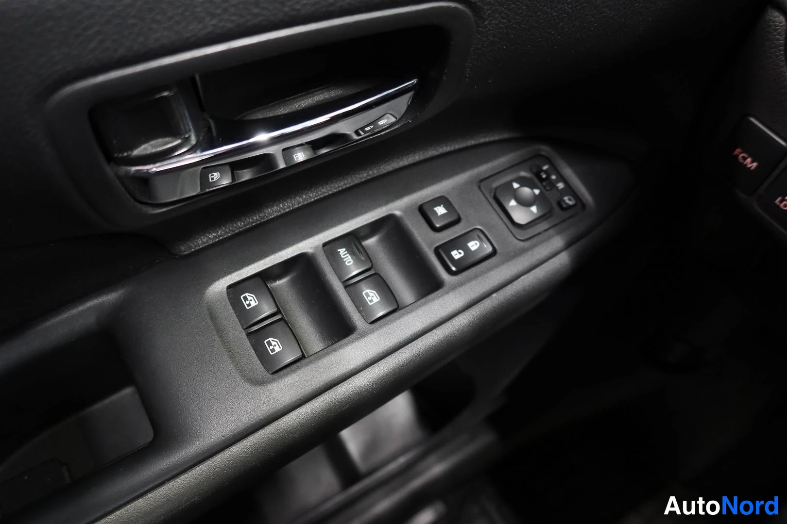 Yksityiskohta: Sisätilan lähikuva: oven sisäpohjan ikkunojen ja peilien kytkimet, yhdessä kytkimessä AUTO-merkintä.