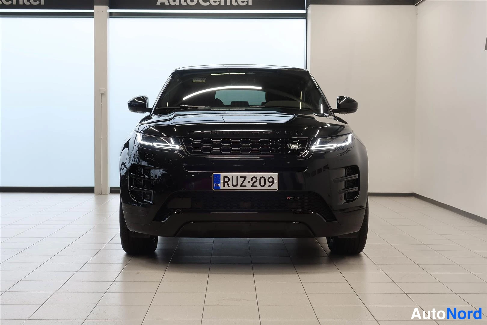 Edestä: Musta Land Rover Range Rover Evoque suoraan edestä kuvattuna sisätiloissa, rekisteritunnus.