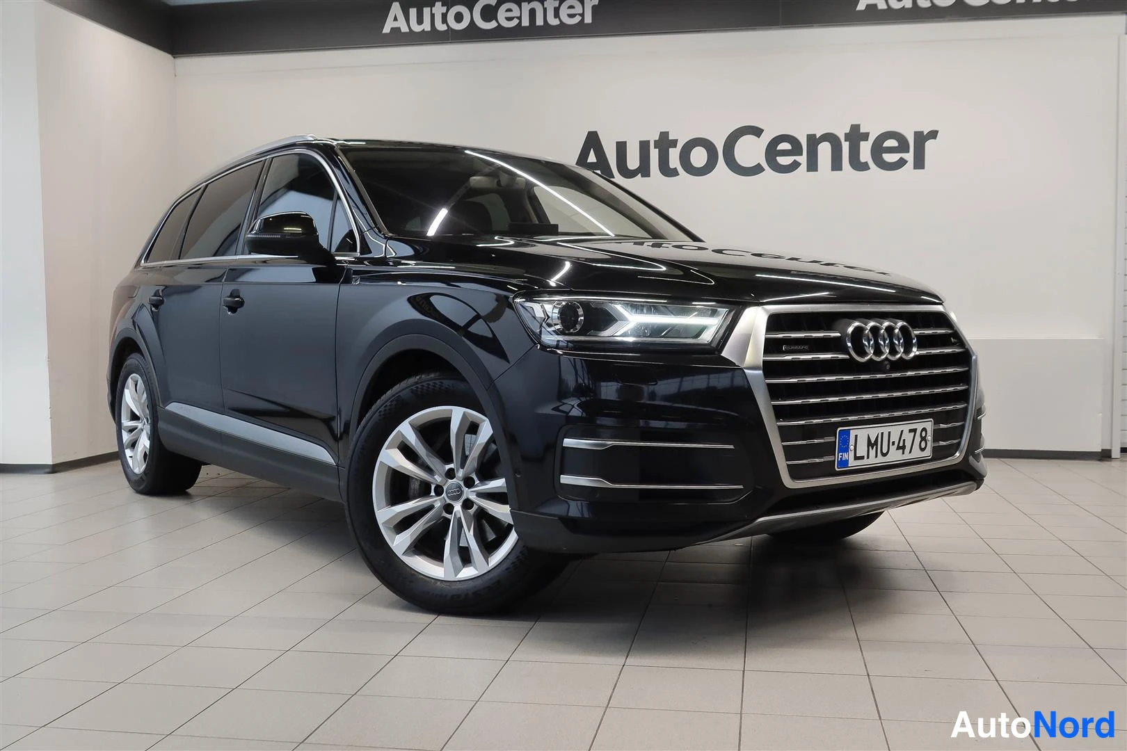 Etuviisto, nokka oikealle: Audi Q7 -series katumaasturi mustana etuviistosta myyntitilassa, rekisterikilpi.