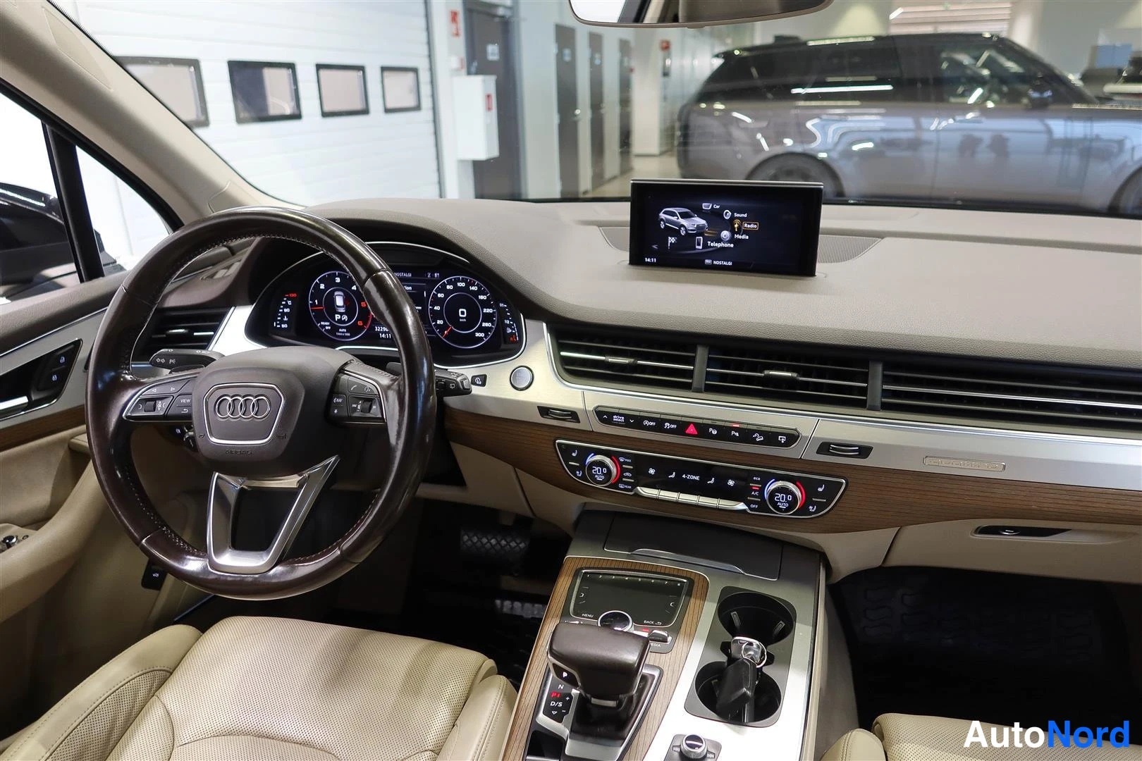 Muu: Audi Q7:n ohjaamon näkymä: Audi-ohjauspyörä, digitaalinen mittaristo, keskinäytön infotainment-näyttö ja kaksivyöhykeilmastointi.