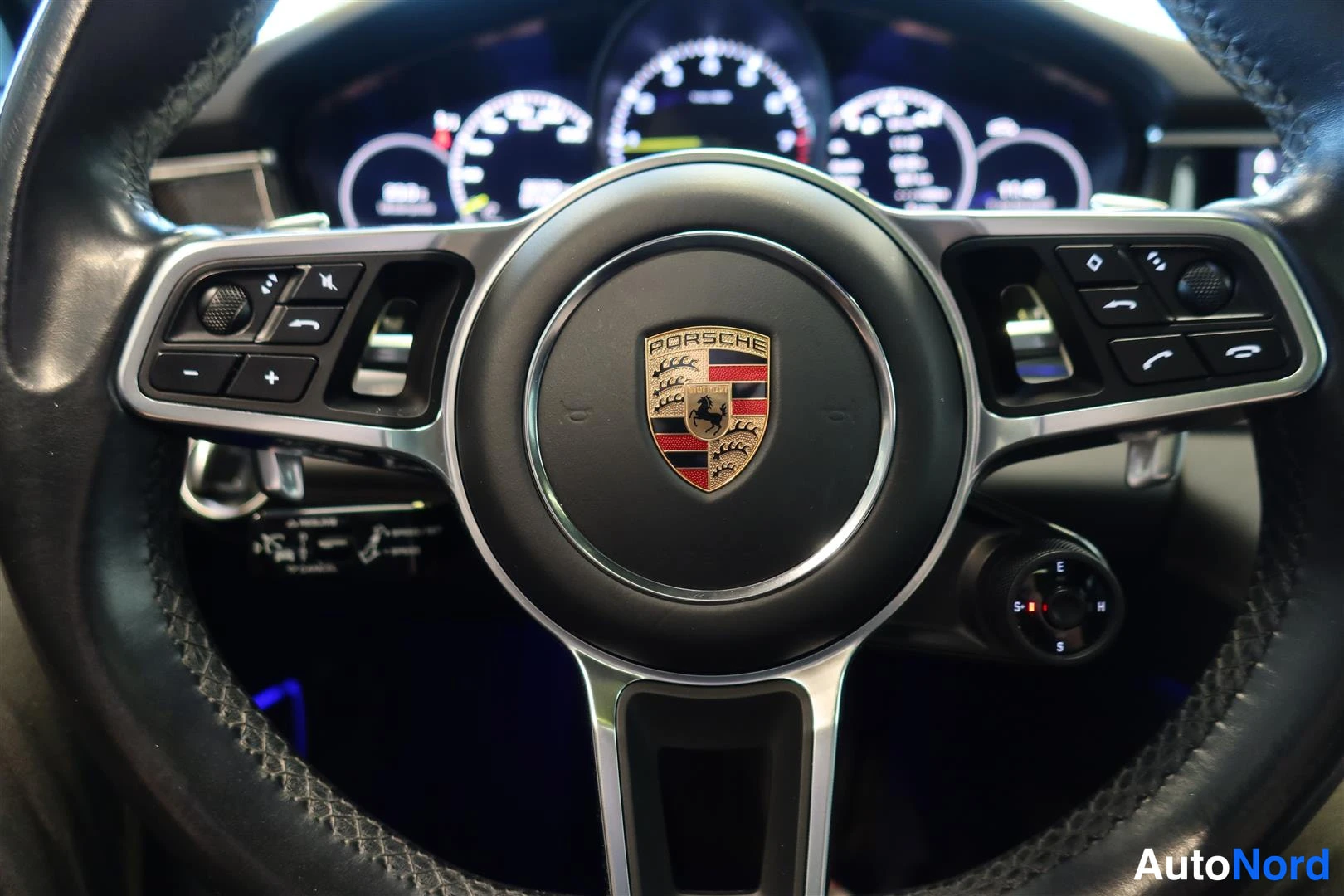 Muu: Ohjauspyörän lähikuva, jossa Porsche-kehyslogo ja nappiryhmät