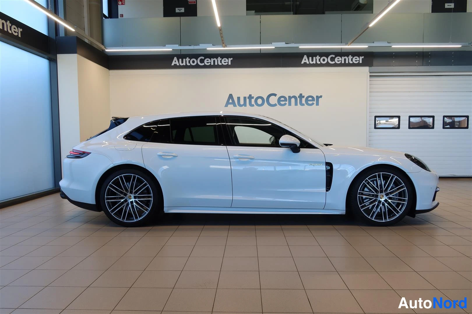Sivulta: Porsche Panamera Sport Turismo sivuprofiilista, valkoinen henkilöauto AutoCenter-hallissa