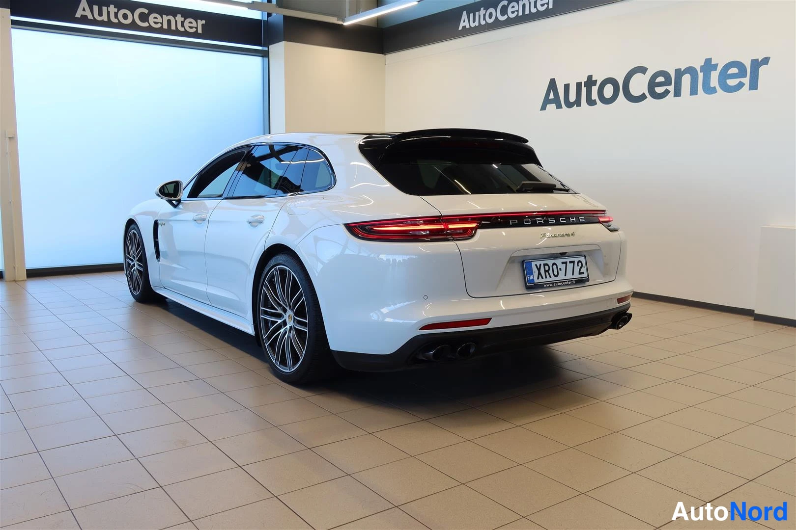 Takaviisto: Taka-nurkanäkymä valkoisesta Porschesta oikealta; näkyvät takavalot, -tunnus, mustat vanteet ja multi-spoke -vanteet.