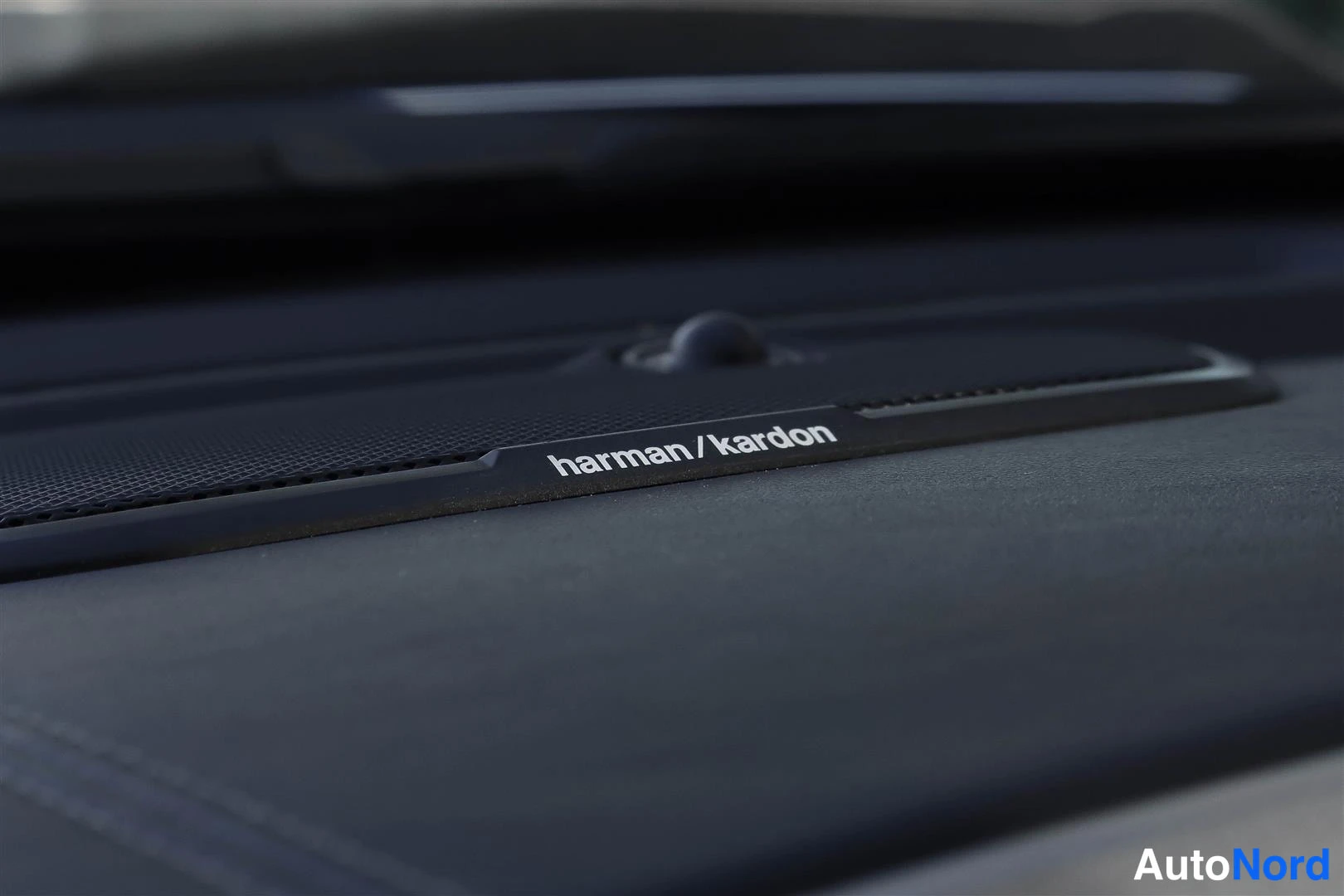 Muu: Sisätilan lähikuva harmaan kaiutinritilän harman/kardon-merkinnästä.