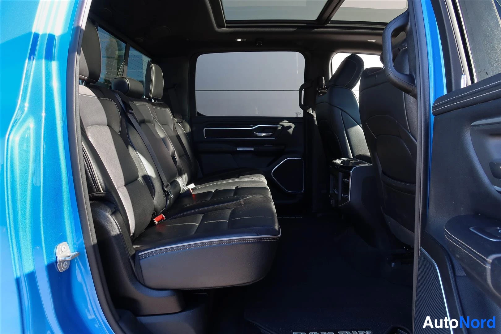 Muu: Sinisen kuorma-autin takapenkkien näkymä mustasta penkkilististä ja lasikattoon.