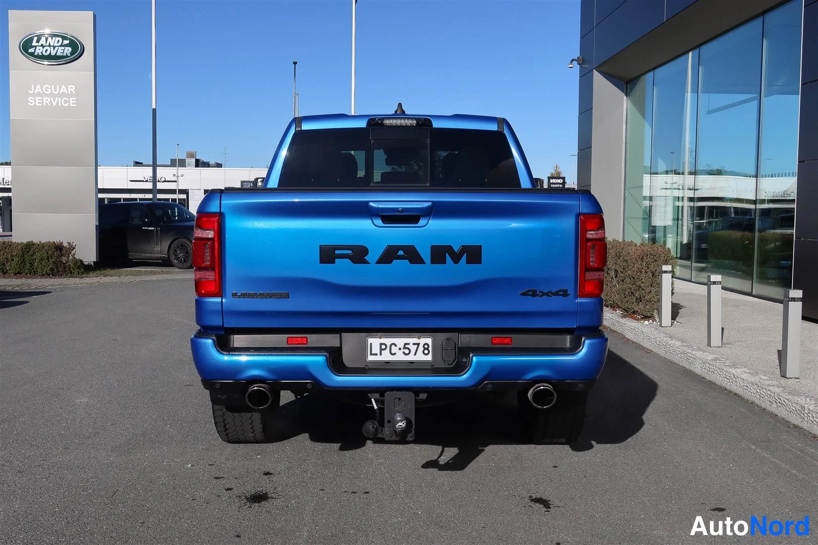 Takaa: Sininen RAM-pick-up suoraan takaa kuvattuna. Tavaramerkkiteksti RAM lavan takapaneelissa, tekstit LARAMIE ja 4x4, rekisteritunnus, kaksi pakoputkea ja hinattava