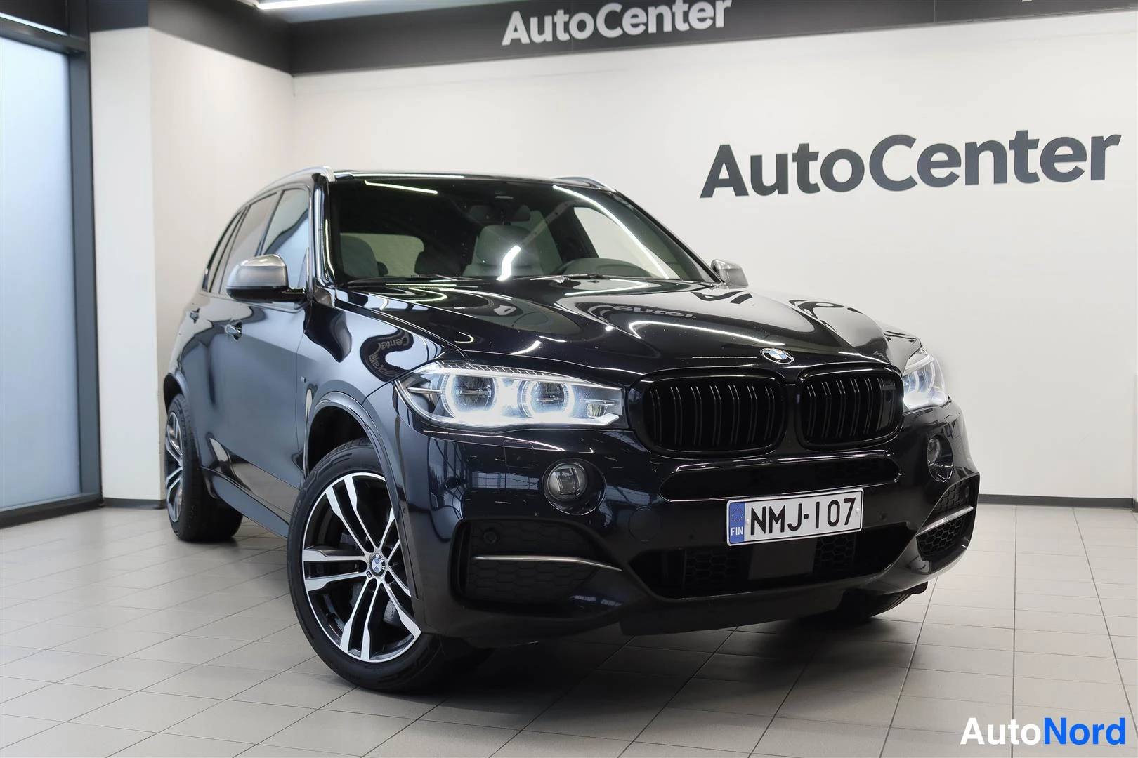 Etuviisto, nokka oikealle: Auton etukulma, etupää oikealla; mustansininen kori, BMW-merkki ja rekisterikilpi näkyvät sisätiloissa.