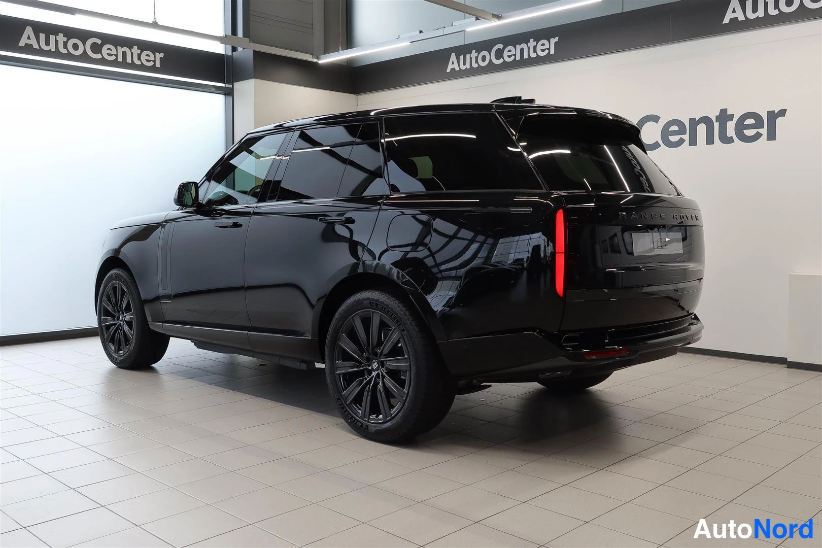 Takaviisto: Musta maastocar hännästä ja sivusta kuvattuna AutoCenter-tilassa; takavalo ja mustat vanteet näkyvät.