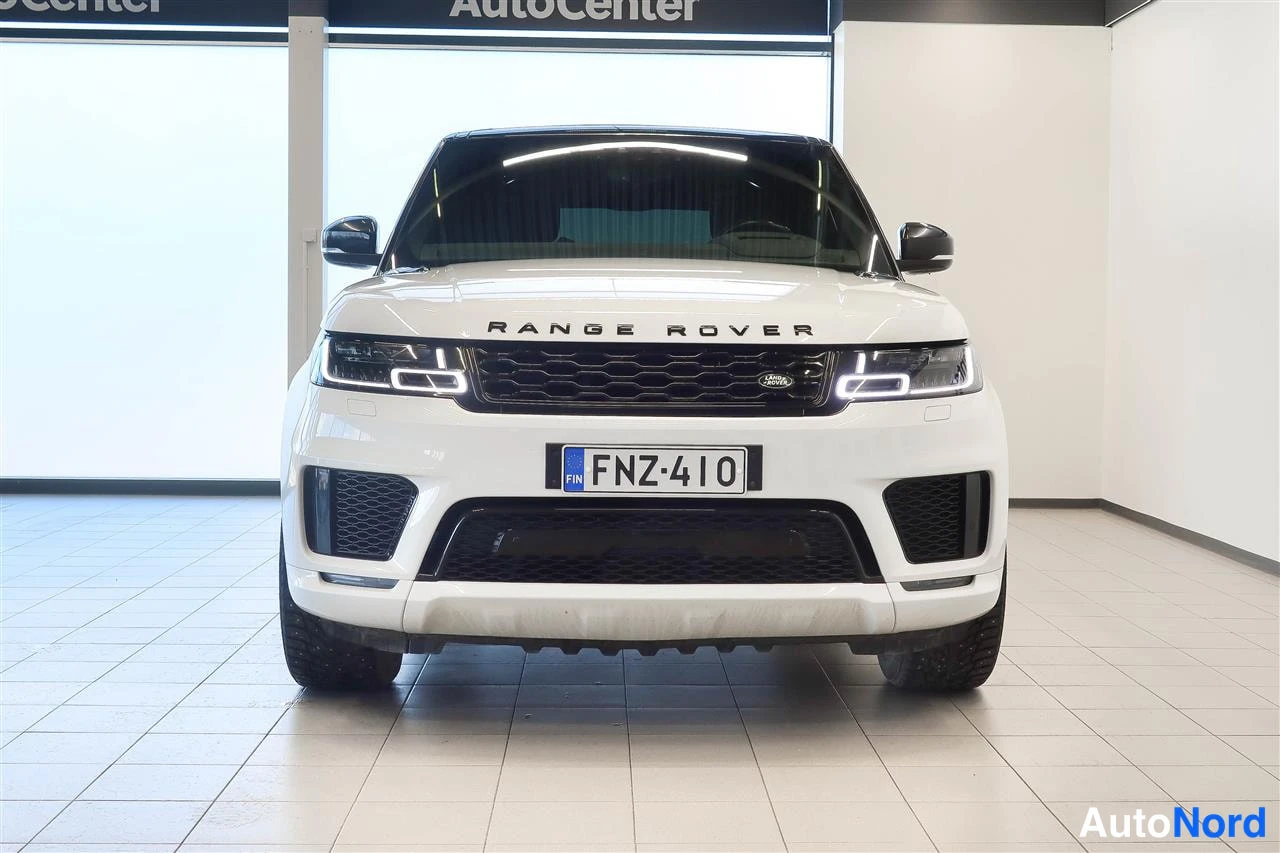 Edestä: Valkoisen Land Rover Range Rover Sport -maastoajoneuvon etunäkymä edestä, rekisteritunnus, musta etusäleikkö ja LED-ajovalot.