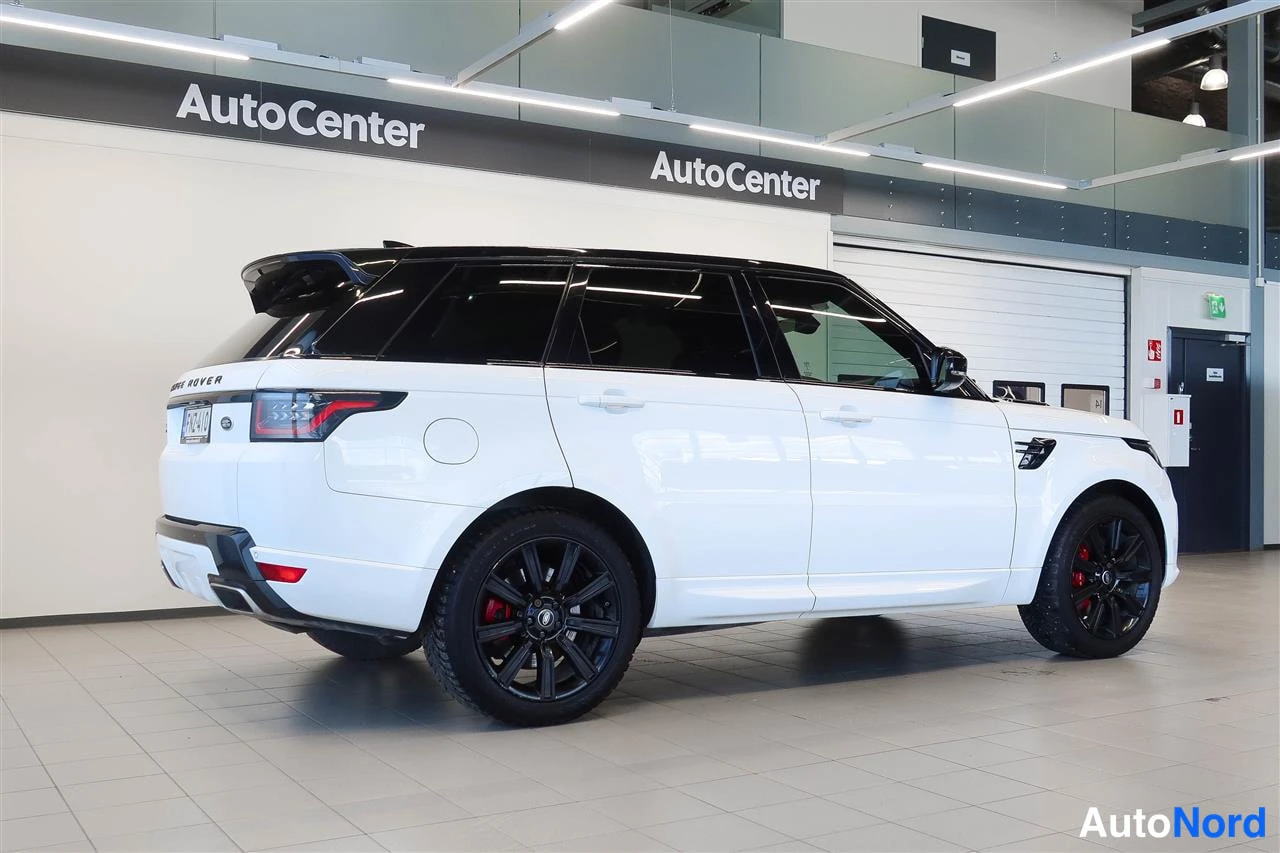 Takaviisto: Valkoinen Range Rover Sport takaviistosta nähtynä autosalissa, mustat vanteet ja musta katto