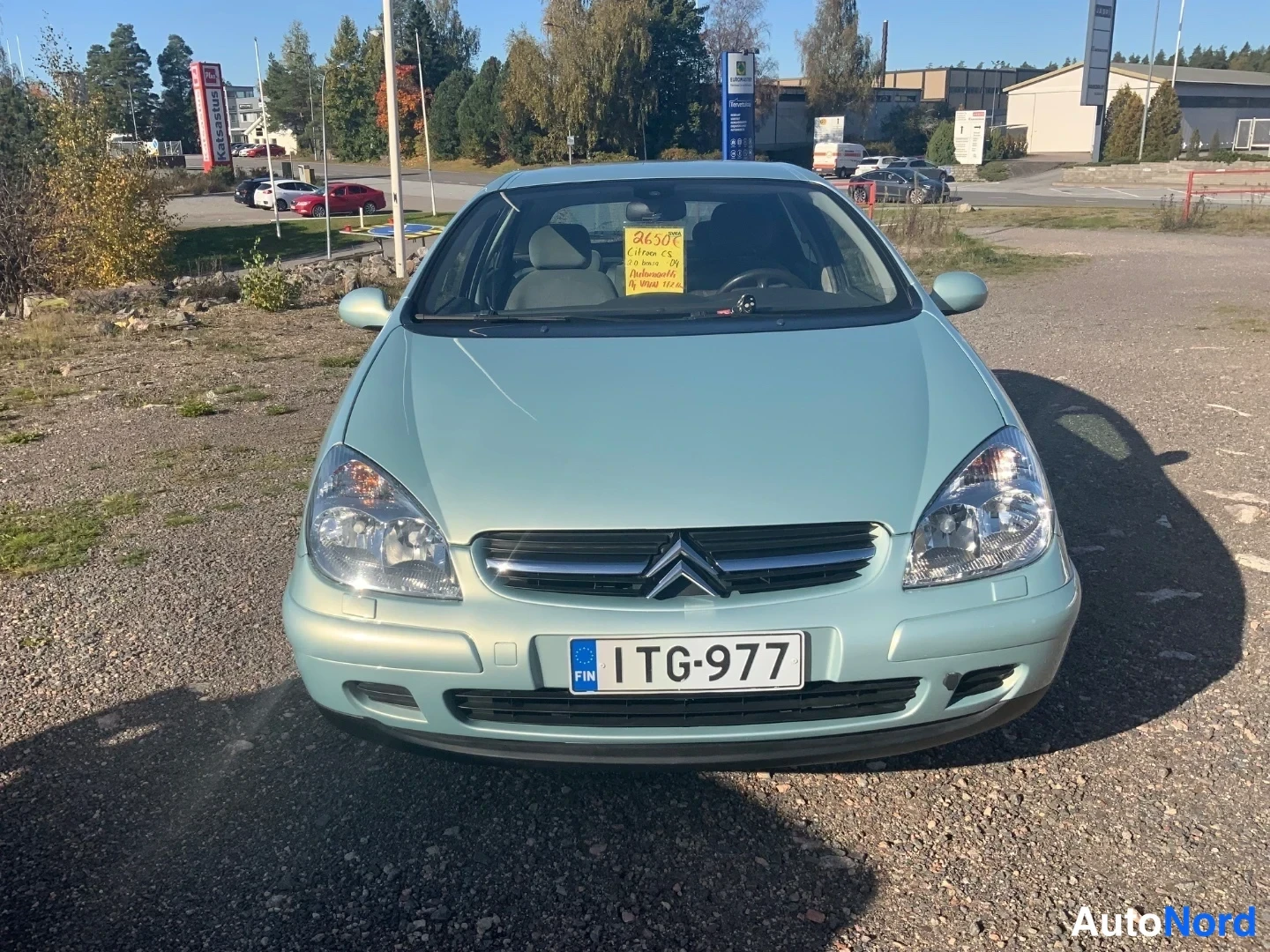 Edestä: Citroën C5 viistoperä suoraan edestä; etusäleikkö, Citroënin logo, ajovalot ja rekisteritunnus näkyvät, tuulilasissa keltainen merkintälappu.