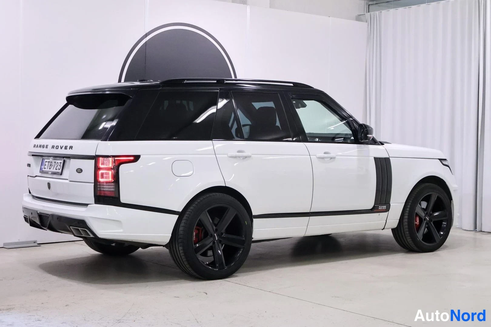 Takaviisto: Valkoinen Land Rover Range Rover takaviistosta sisätiloissa, musta katto ja mustat vanteet näkyvät.
