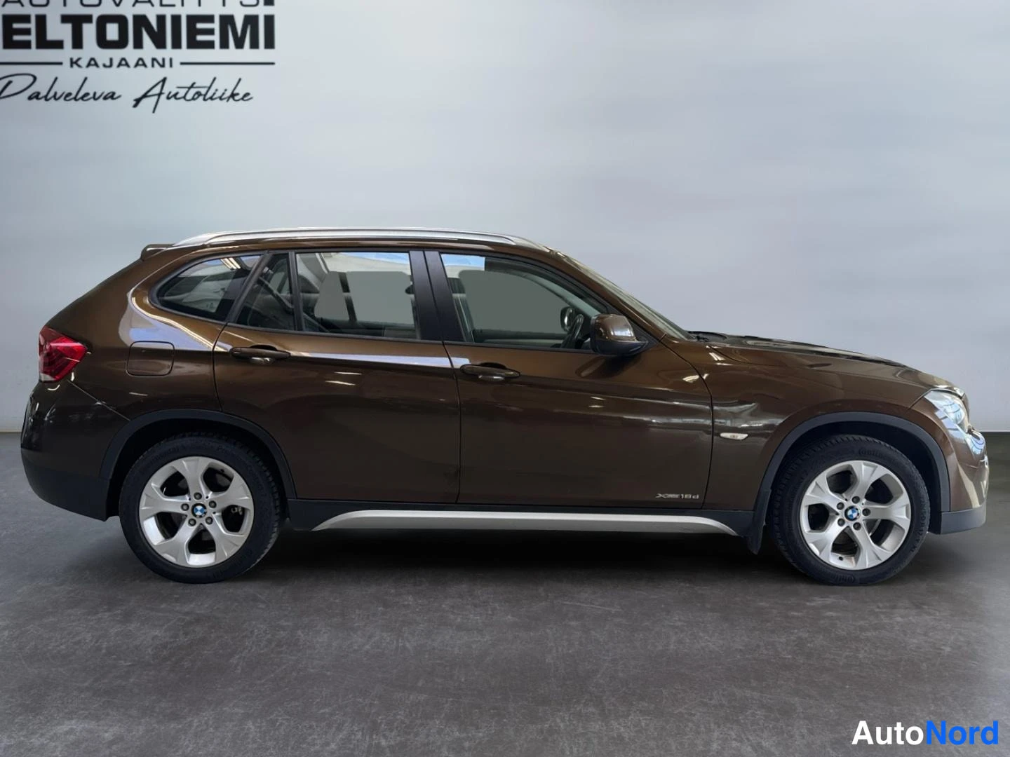 Etuviisto, nokka oikealle: BMW X1:n kylki sivusta oikealle, ruskea väri ja hopeiset metallivanteet.