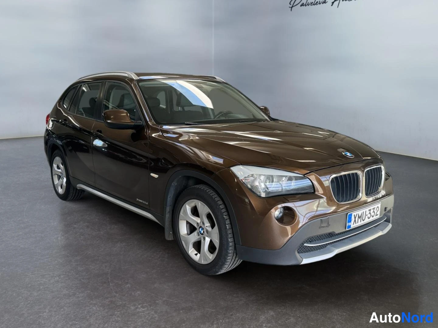 Etuviisto, nokka oikealle: BMW X1 kulma-etukuva oikealta auton ollessa ruskea, rekisterikilpi.