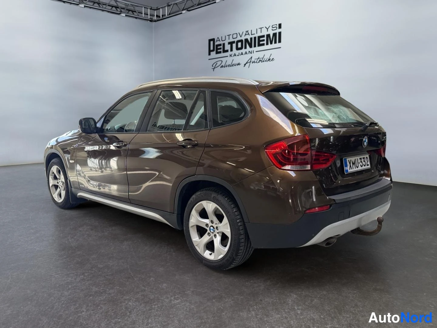 Takaviisto: BMW X1 takaa vasemmalta nähtynä, rekisteritunnus, perävaunukoukku näkyy.