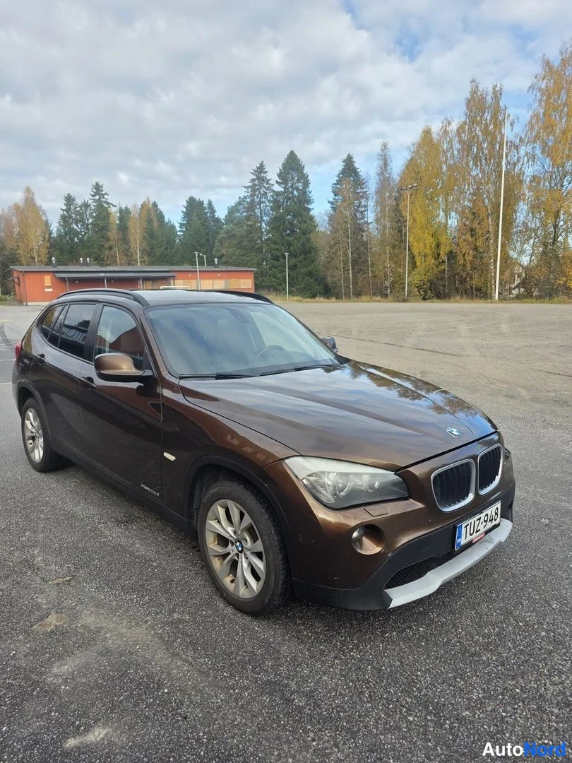 Etuviisto, nokka oikealle: Ruskean BMW X1:n etukulman kuva, keula oikealla, rekisteritunnus.