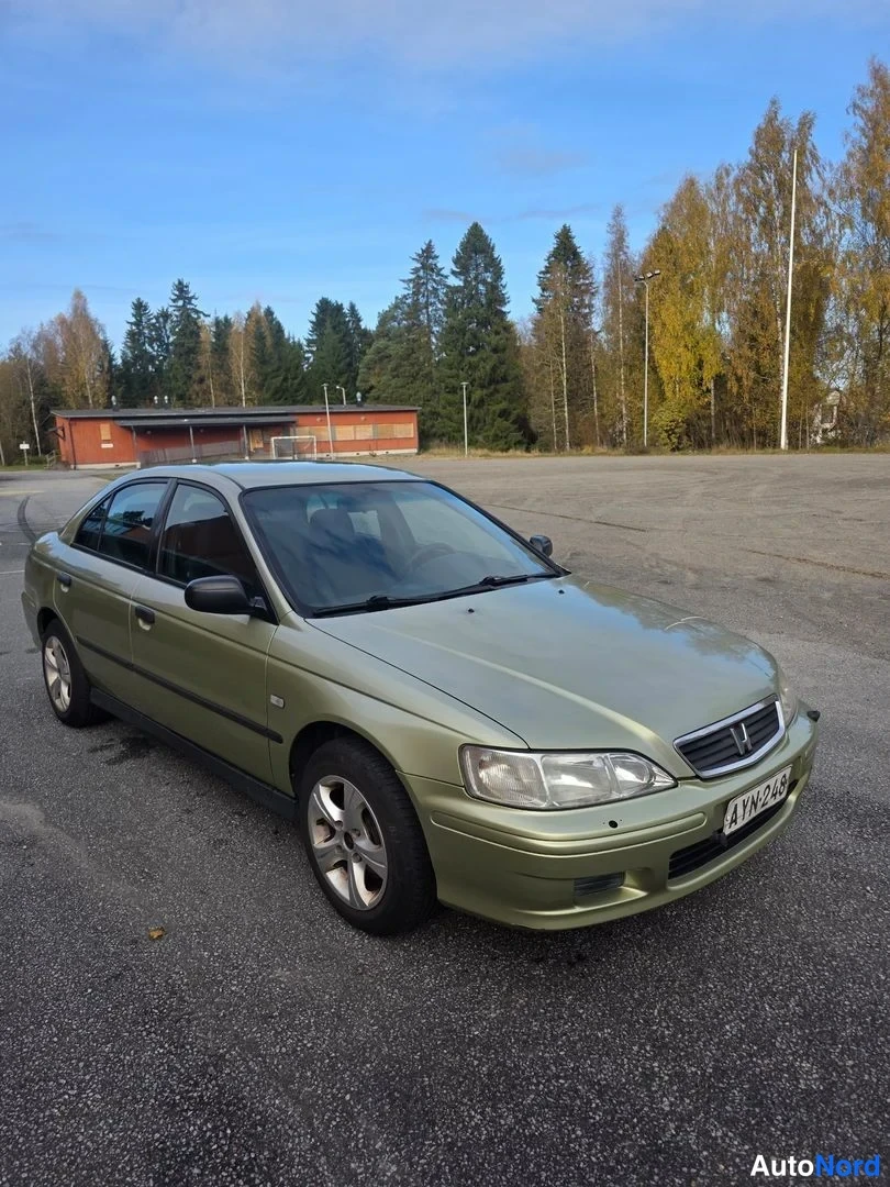 Etuviisto, nokka oikealle: Vihertävä Honda Accord -sedan kolmesta neljänneksestä etuvasemmalta kuvattuna; etupaneeli ja kylki näkyvät, rekisteri.