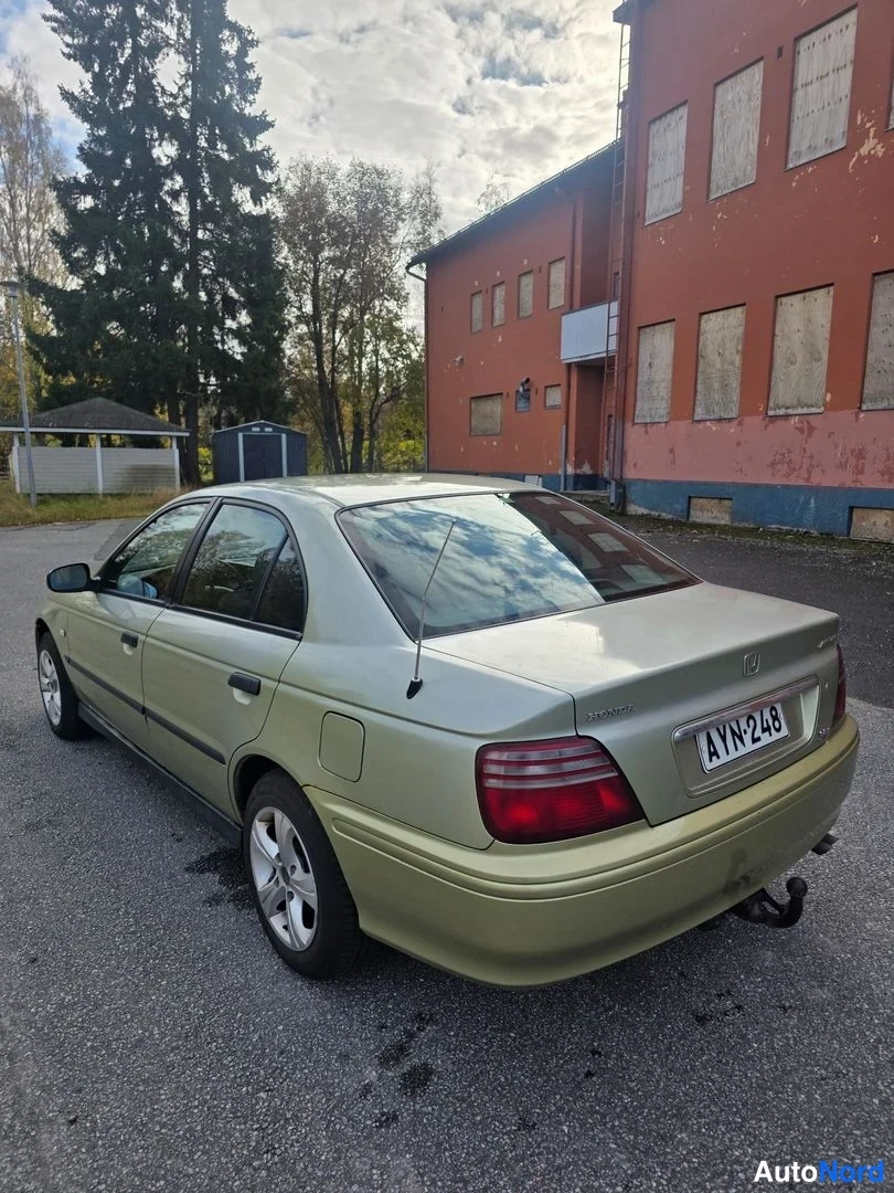 Takaviisto: Vaaleanvihreä Honda Accord -sedan takakolmanneksen kuvattuna rakennuksen edessä; takapaneeli ja kylki näkyvät, rekisteri.