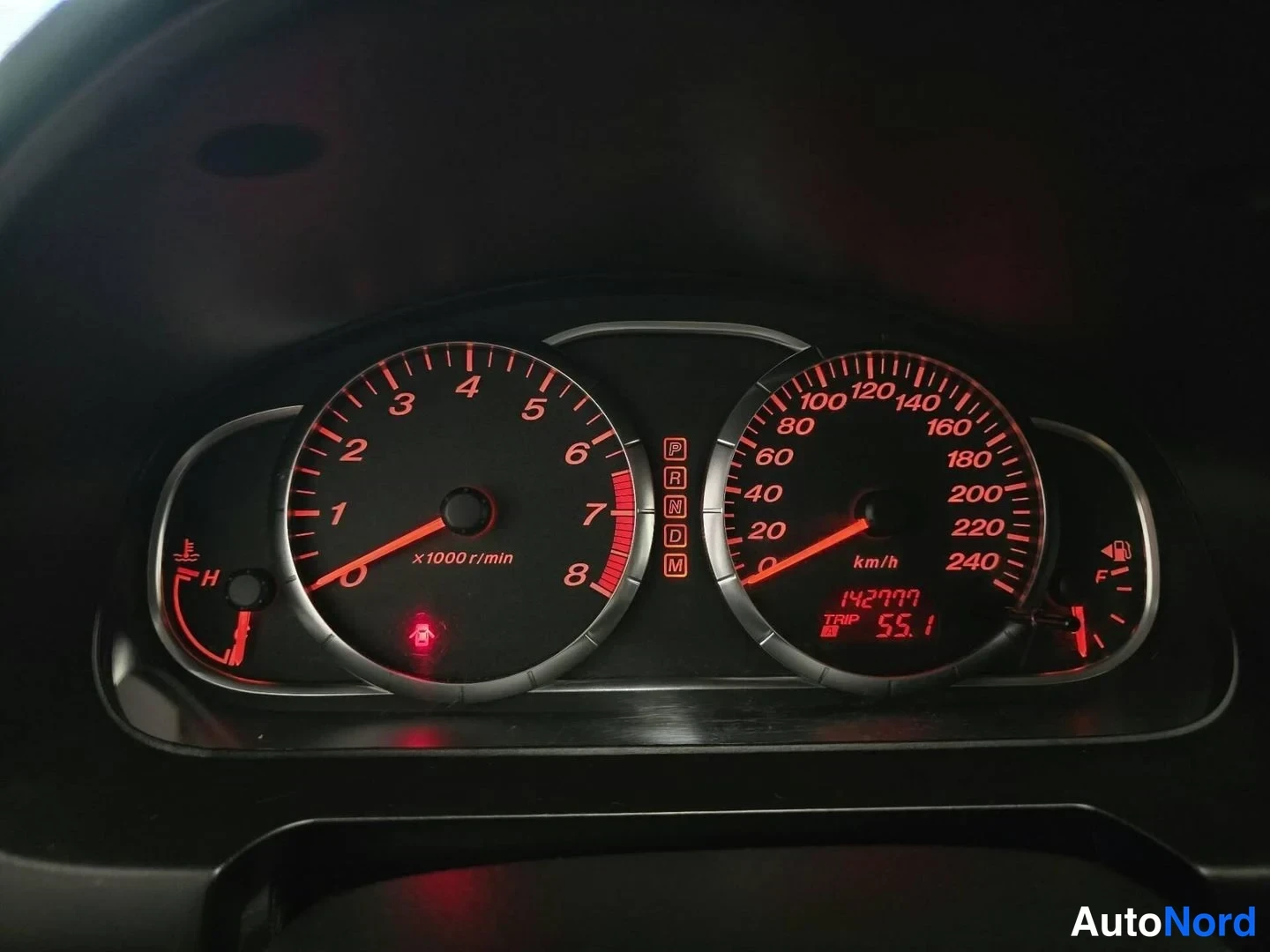 Yksityiskohta: Mittaustaulu punavalaistuksella: kierroslukumittari ja nopeusmittari 0–240 km/h, matkanmittari näyttää 142077 km.