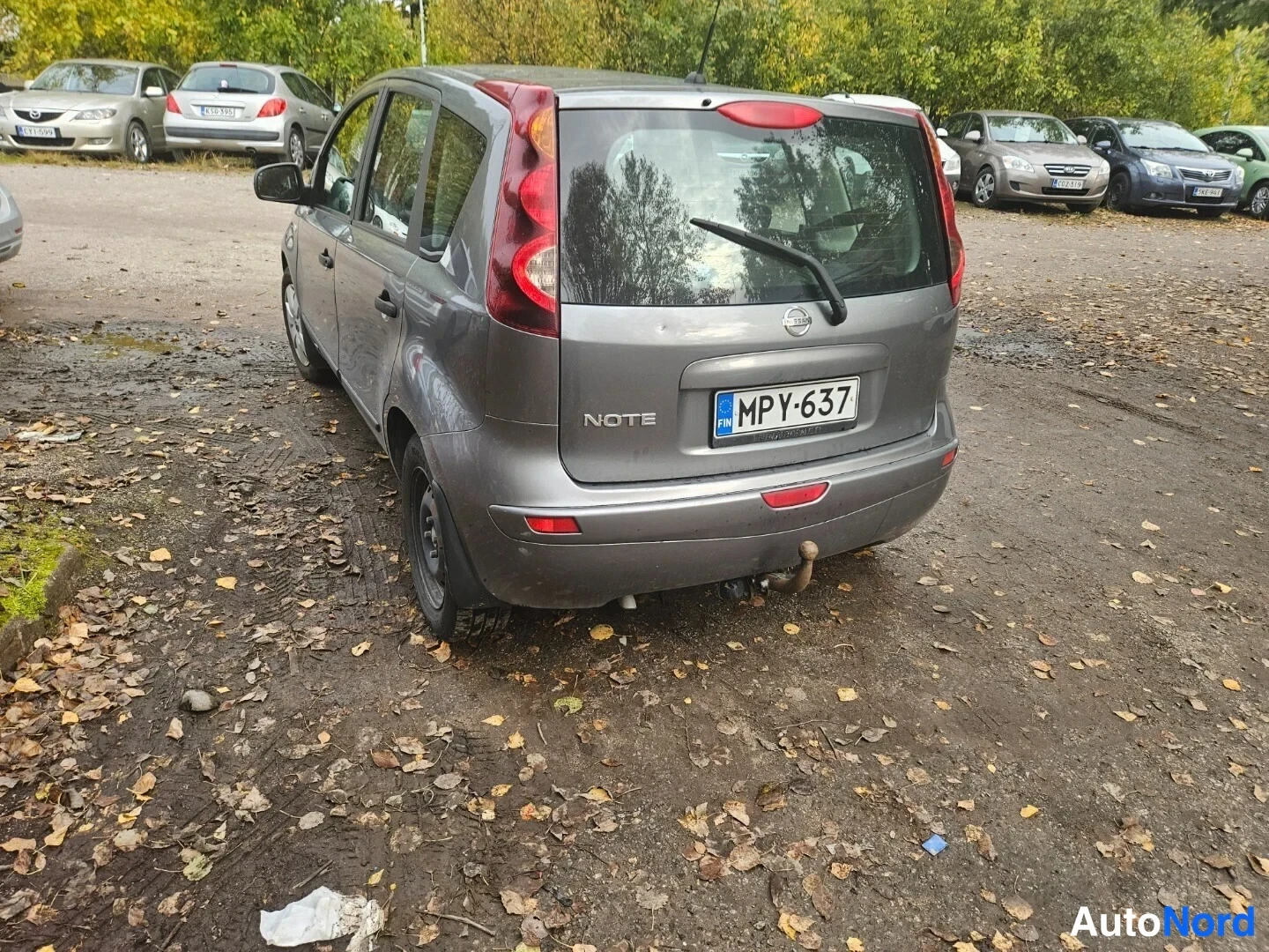 Takaviisto: Harmaa Nissan Note suoraan takaa, peili toisella sivulla, rekisteritunnus ja takalasin pyyhkijä näkyvissä.