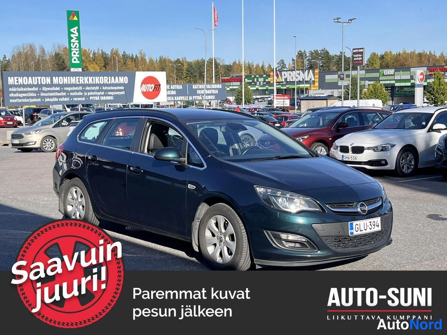 Etuviisto, nokka oikealle: Opel Astra Sports Tourer -farmari tummansinisenä tai tummanvihreänä etukulmasta oikealta parkkipihalla, rekisteritunnus.