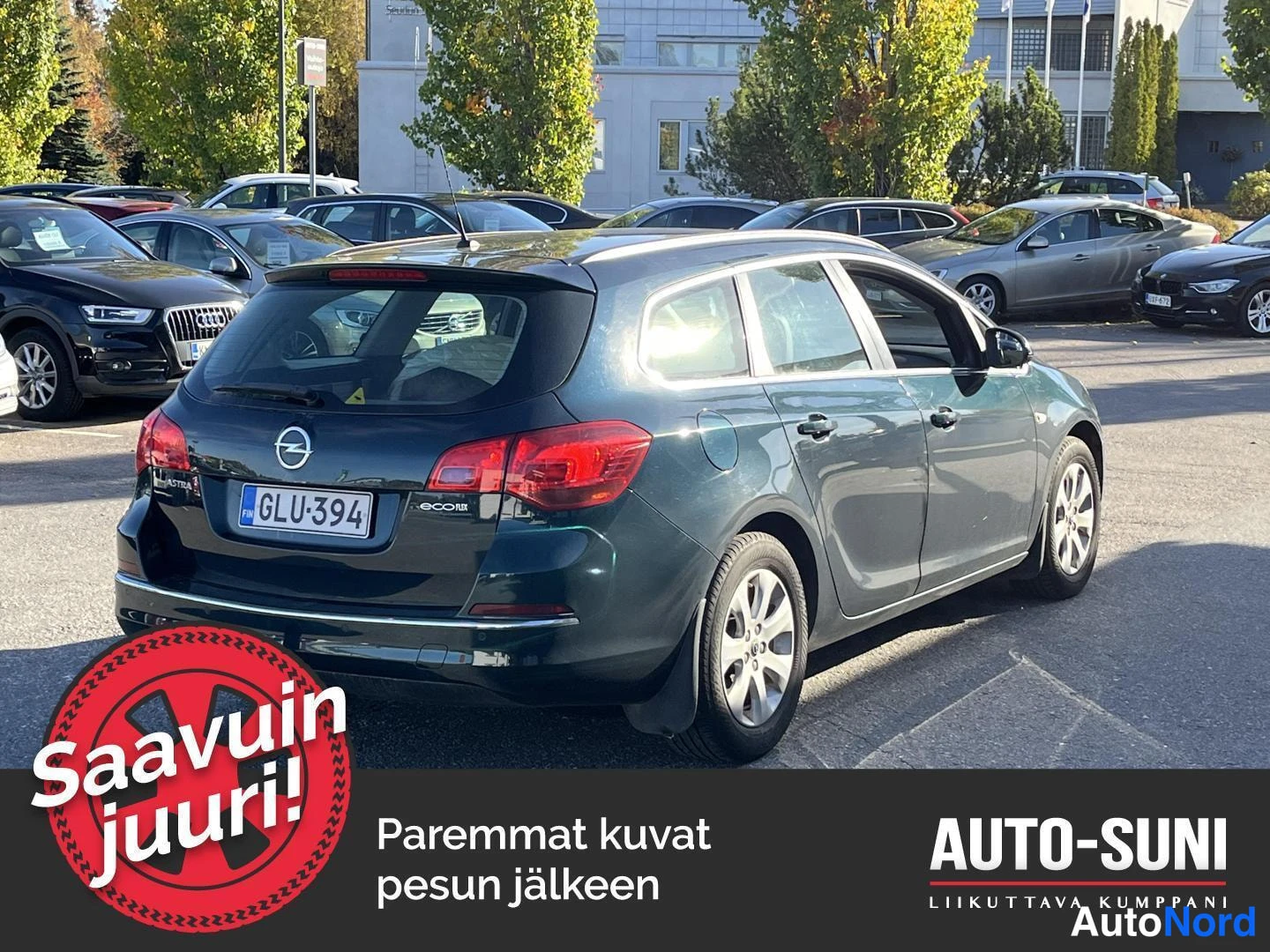 Takaviisto: Opel Astra Sports Tourer -farmari tummansinisenä tai tummanvihreänä takakulmasta vasemmalta parkkipihalla, rekisteritunnus.